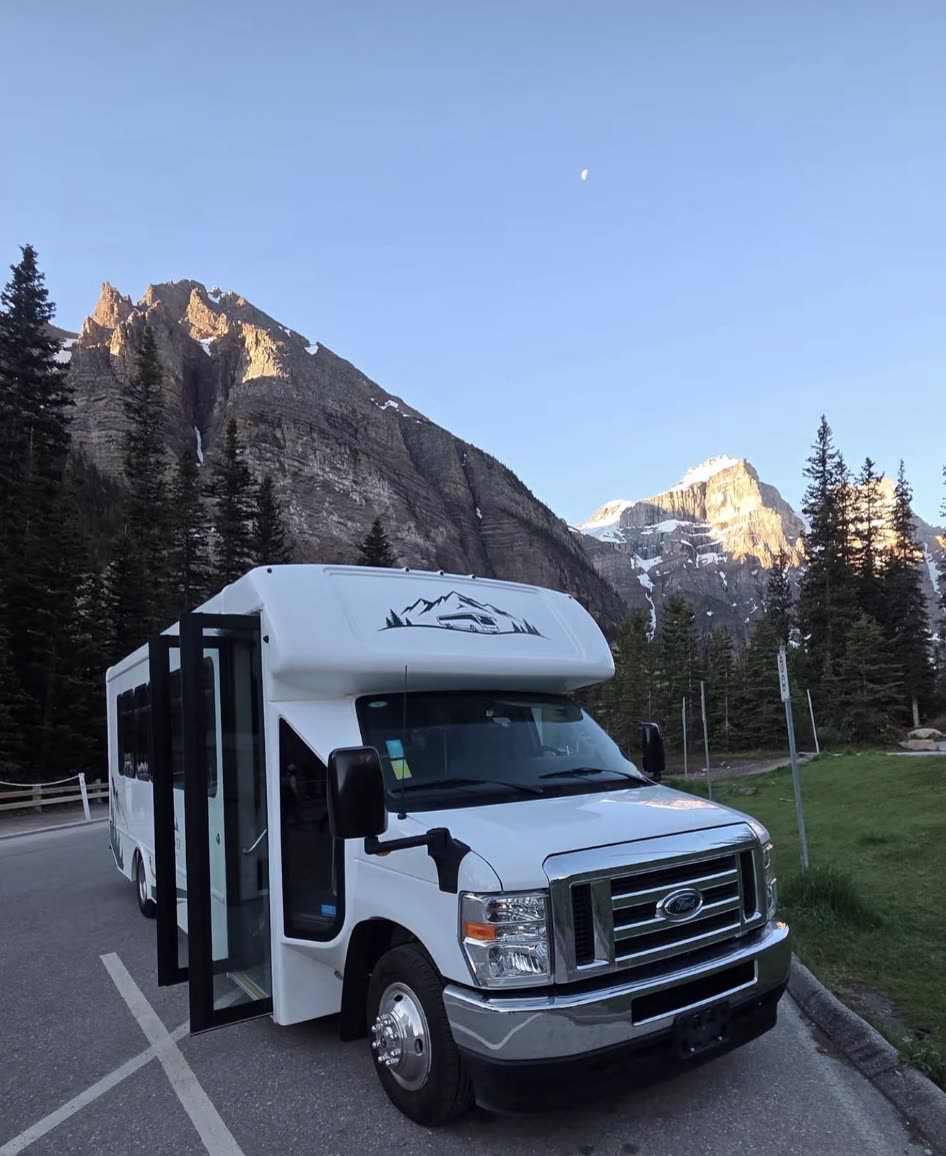 The RockFlower coach parked at the Moraine Lake staging area at golden hour